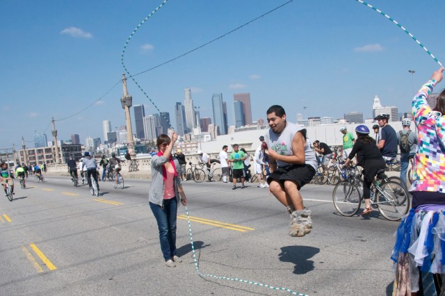 Man Double Dutch jump roping on a city street closed off to cars with the L.A. skyline in the distance.